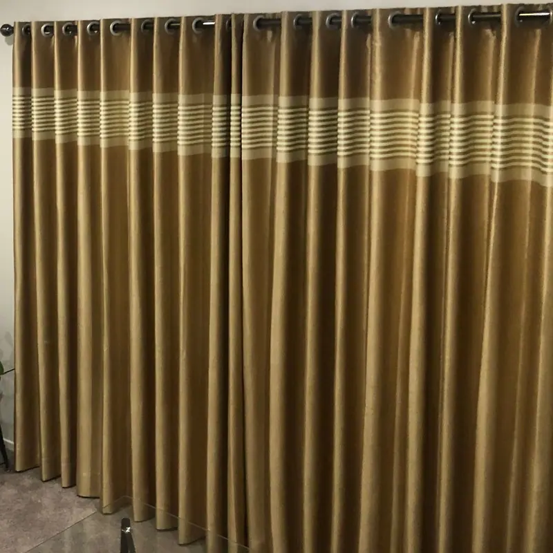Gold eyelet curtains with a cream stripe on a chrome rod