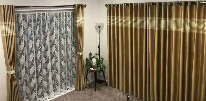 Living room with gold striped eyelet curtains and a leaf-pattern lace sheer