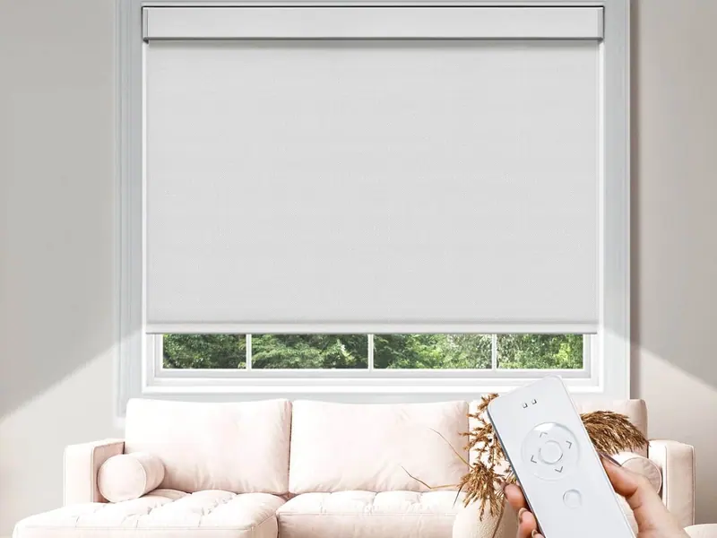 White motorised roller blind with a handheld remote control