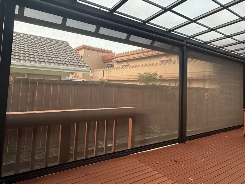 Sunscreen mesh outdoor blinds lowered around a timber deck