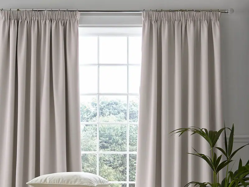 Pencil pleat curtains in a soft blush fabric framing a tall window