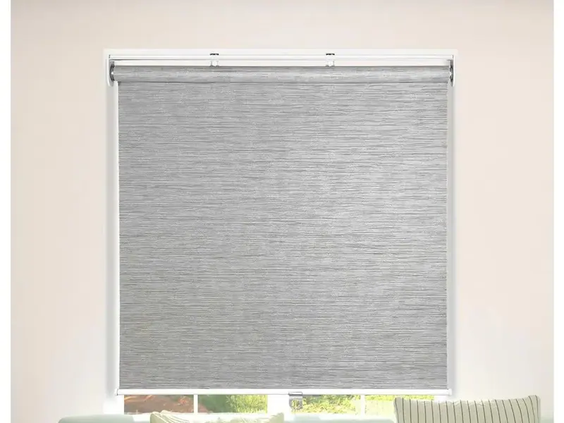 Textured grey roller blind above a sofa with patterned cushions