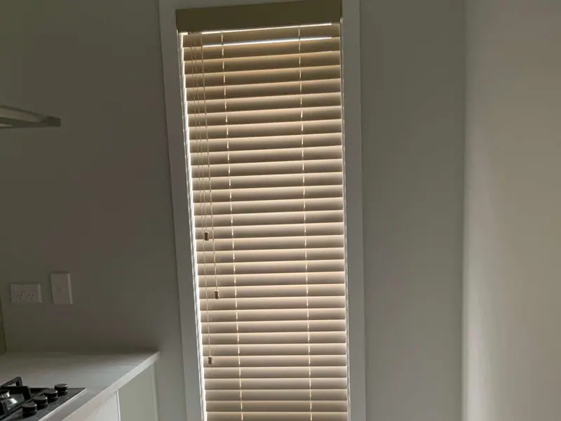 Wooden venetian blind on a tall door beside a white kitchen
