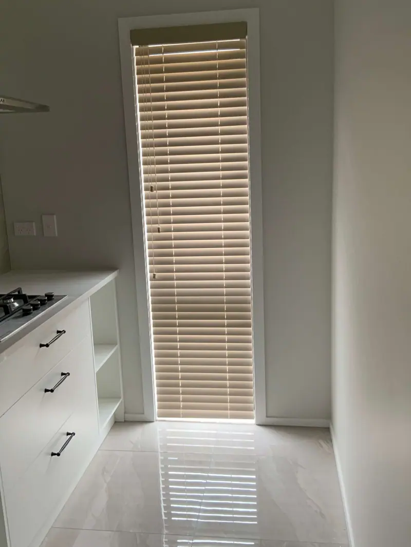 Wooden venetian blind on a tall door beside a white kitchen